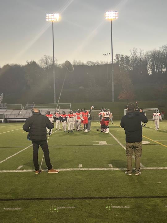 Jim Kulakowski and Kellen Dengler capturing video and audio on a football field