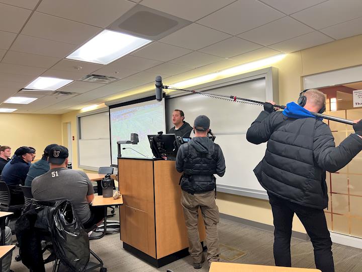 Jim Kulakowski holding a boom pole to capture vérité audio